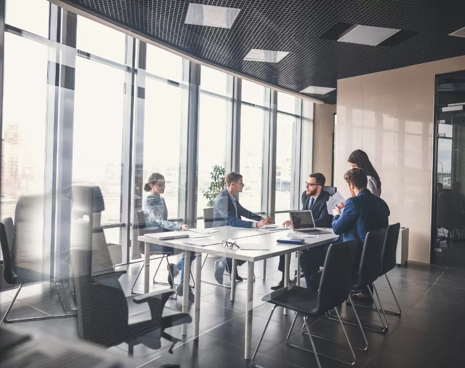 A imagem reflete uma sala de reunião com pessoas conversando sobre negócios